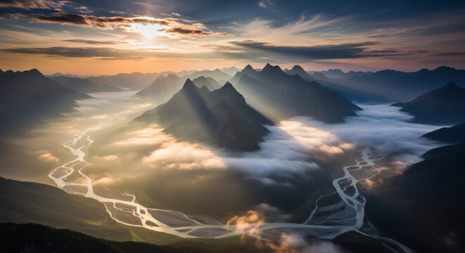 Aerial view of a serene mountain range with a winding road, shrouded in fog and illuminated by sunrise beams, against a vibrant sky.
