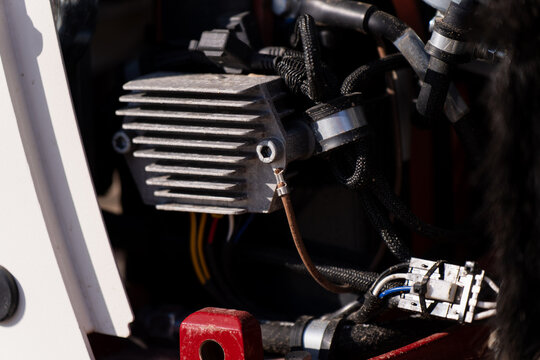 Industrial electrical unit with metal fins, wiring harness and hose connections in machinery housing, highlighting repair and electrical service work