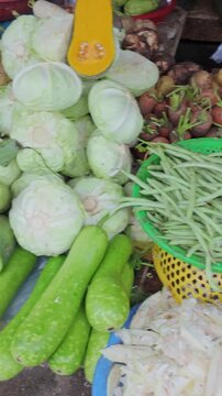 A person shops for fresh produce at Dong Ba Market, selecting from tomatoes, peppers, limes, and other vegetables. Dong Ba Market,