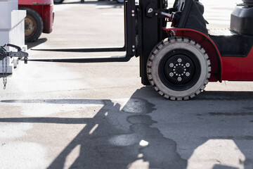 Red forklift with extended forks beside a trailer hitch on concrete ground, highlighting material handling, warehouse logistics and loading operations © K