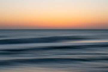 Abstract long exposure of golden sunset over dark blue ocean wav