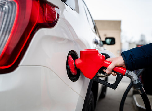 Close up of hand on fuel nozzle filling the tank of car with gas.