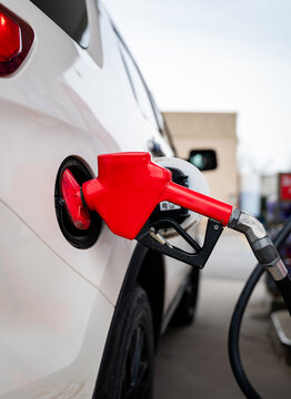 Close up of fuel nozzle of gas pump filling the tank of a vehicle.