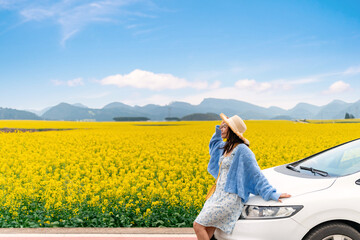 Fototapeta premium Happy young woman enjoying the canola fields while traveling to Luoping County in China, Road trip on vacation