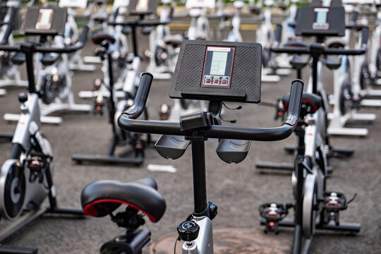 Rows of stationary bikes ready for an indoor cycling workout class in a gym