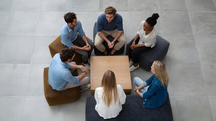 Fototapeta premium Overhead perspective of a diverse group of people engaged in a casual collaborative meeting around a central wooden table