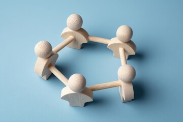 Obraz premium Connected Circle: A symbolic representation of unity and interconnectedness. Wooden figurines link arms, forming a cohesive circle against a backdrop of soft blue.