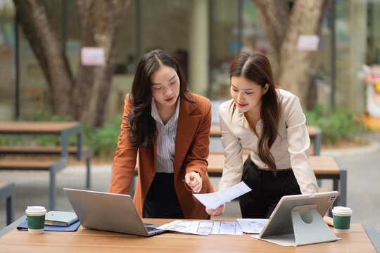 Two female coder or developer working overtime using a computer display in problem solving.