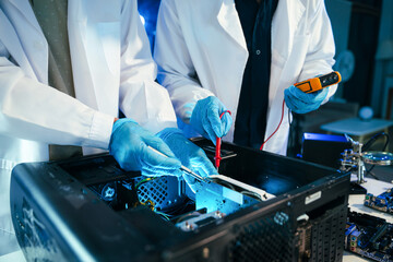 Engineers testing computer hardware with multimeter inside technology laboratory. Electronics repair, motherboard diagnostics © Nuttapong punna