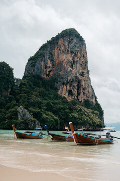 Long tail boats in front of limestone cliff at Railay West Beach