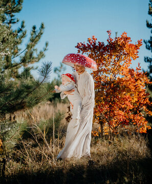Mother and baby as fly agaric mushrooms in autumn forest