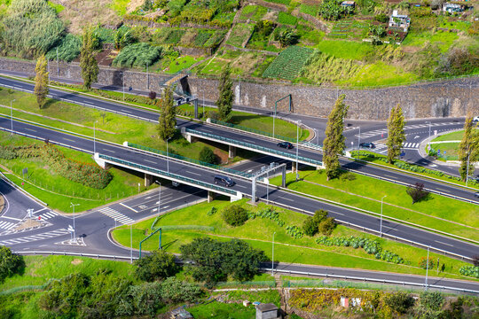 Aerial view of a modern highway interchange with multiple lanes, green landscaping, and vehicles navigating through roundabouts and overpasses in a rural setting