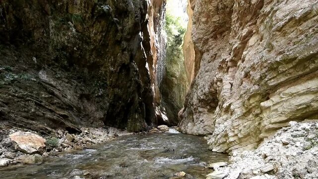 stream in a mountain gorge, waterfall in the background, rocks on the sides