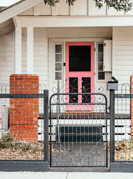 Pink entry door & iron gate on a street.