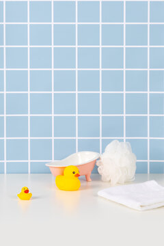 Pastel blue tile bathroom with pink bathtub white towel and yellow rubber duck