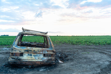 Fototapeta premium Destroyed and burnt car in the fields, accident or war concept