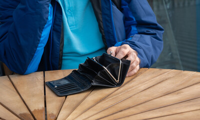 Fototapeta premium Empty wallet in hands close-up. A black wallet with no money, poor person, economy crisis