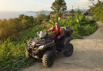 Fototapeta premium A man engages in extreme ATV riding on mountains in the evening