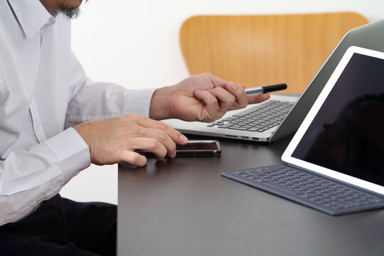 Businessman Working with Smartphone, Tablet and Laptop at Modern Office Desk