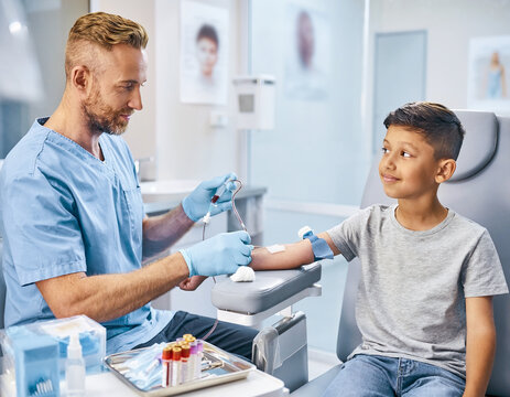 Male medical professional collecting a blood sample arm of a kid at hospital