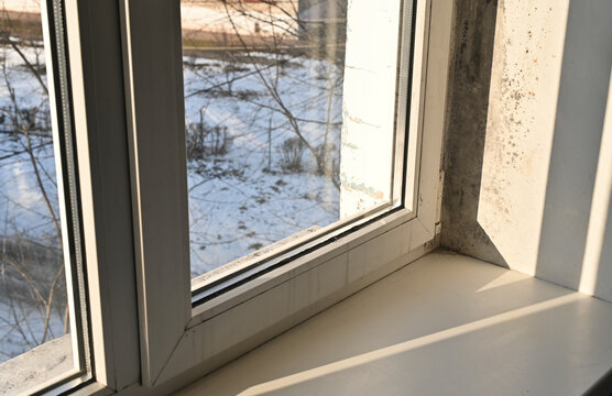 mold by the window. sunlight illuminates the moldy wall by the window. Signs of high humidity and poor ventilation in the room.