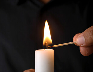 Mano encendiendo una vela con una cerilla de llama brillante en ambiente oscuro, concepto de iluminación, calma, espiritualidad, ritual y momento íntimo de luz, calma y paz o dia de todos los santos
