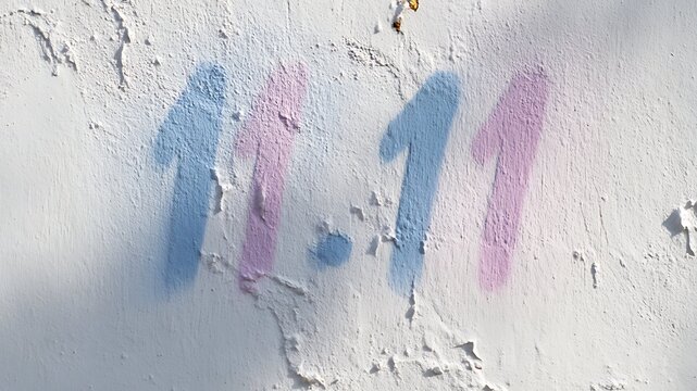 "11:11" angel number graffiti on white textured wall, spiritual numerology concept
