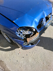Abandoned wreck of a car sitting on a street in a city during midday with visible damage and rust