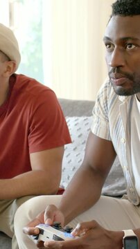 Vertical video: Leaning right player pressing white controller on couch at home, celebrating win
