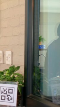 Vertical video: Entering woman in yellow knit holding box at cafe, showing QR sign, copy space