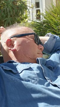 Vertical video: Panning camera revealing couple relaxing on patio showing sunglasses, denim shirt