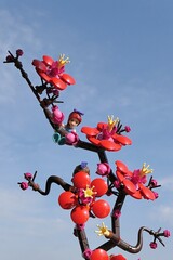 Fototapeta premium LEGO Friends figure of Mia hanged on LEGO Botanicals Plum Blossom branch, blue skies with some scarce clouds in background, spring morning sunshine. 