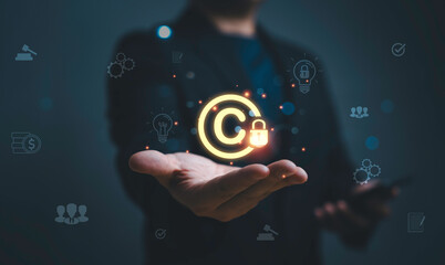 Plakat Businessman holding glowing copyright symbol with lock representing intellectual property protection, digital rights management security, online content ownership and legal protection concept.