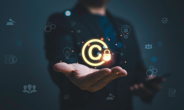 Businessman holding glowing copyright symbol with lock representing intellectual property protection, digital rights management security, online content ownership and legal protection concept.
