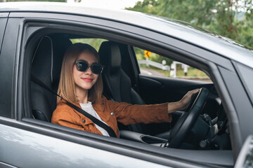 Naklejka premium Young beautiful asian women getting new car. she very happy and excited. Smiling female driving vehicle on the road on a bright day.