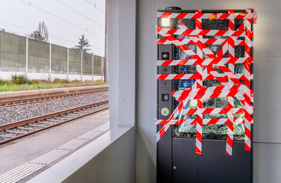 Broken Vending Machine with Red Warning Tape and Shattered Glass at Train Station After Vandalism