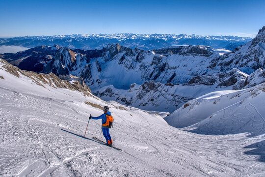 Ski descent from the S&auml;ntis in the Appenzell Alps. Ski tour in the Alpstein region. From Schw&auml;galp to Toggenburg. Ski tour in rugged terrain. Skier enjoys the view of the snow-covered mountains