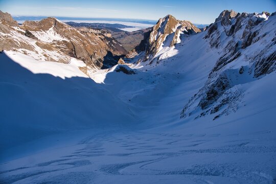 Ski descent from the S&auml;ntis in the Appenzell Alps. Ski tour in the Alpstein region. From Schw&auml;galp to Toggenburg. Ski tour in rugged terrain. Skier enjoys the view of the snow-covered mountains
