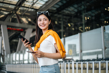 Young asian woman traveler using smartphone for checking flight information check the routes trip...