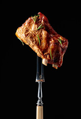 Grilled pork ribs on a fork.