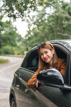 Young beautiful asian women getting new car. she very happy and excited. Smiling female driving vehicle on the road on a bright day.