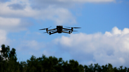 The drone hovered in the sky, flying, propellers spinning. Below you can see the forest....