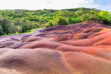 Seven Colored Earth dunes in Chamarel Mauritius with red and purple volcanic sand formations and tropical forest background.