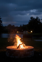 Fototapeta premium Cozy outdoor fire pit burning brightly in a beautiful residential backyard at dusk, creating a warm and relaxing atmosphere for evening entertainment.