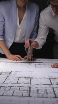 Professionals working on building plans and schematics, developing architecture and engineering projects with precision tools. Concept of architecture and business in low key lighting