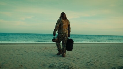 Soldier walks down beach toward ocean ready for rescue by dinghy © Polonio Video
