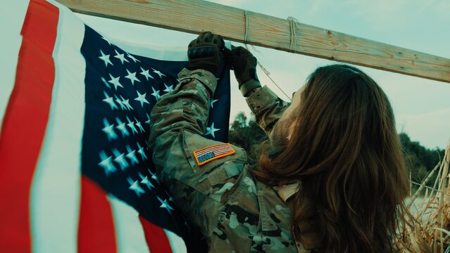 American soldier prepares flag to honor fallen soldiers on Memorial Day in a hut
