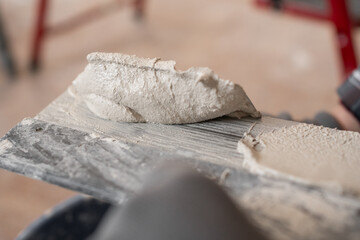 Close up of wet plaster material on metal trowel for wall finishing