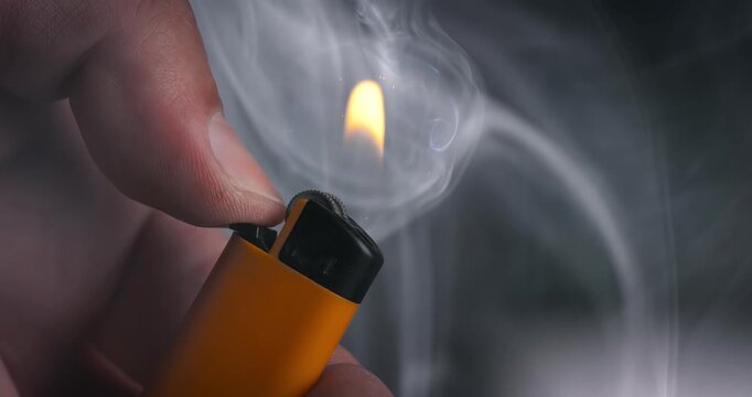 Burning lighter with rising smoke in human hand. Shot on super slow motion camer.
