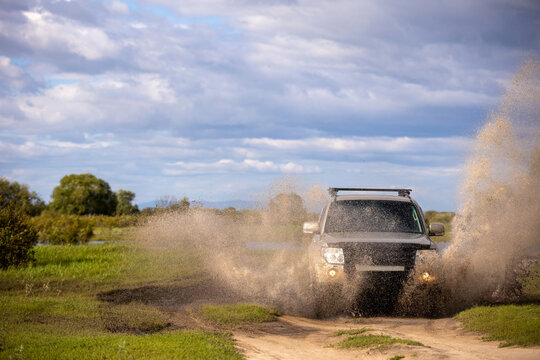 Japanese SUXV moving by a puddle making a lot of water splashes